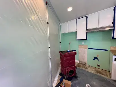 Containment plastic and a red dehumidifier in a kitchen with the cabinets opened up