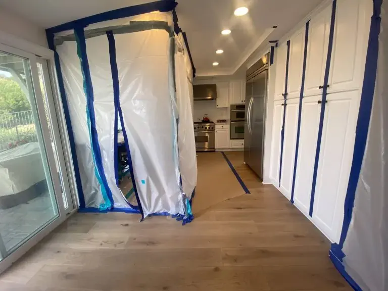 Containment walls and drying gear set up in a kitchen beside a sliding glass door in a La Habra home