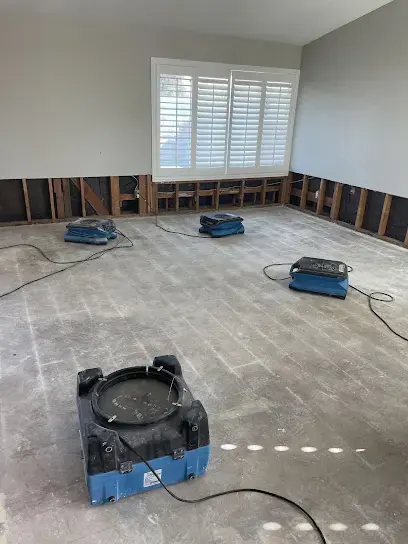 Air movers drying a large open floor after the carpet was pulled out