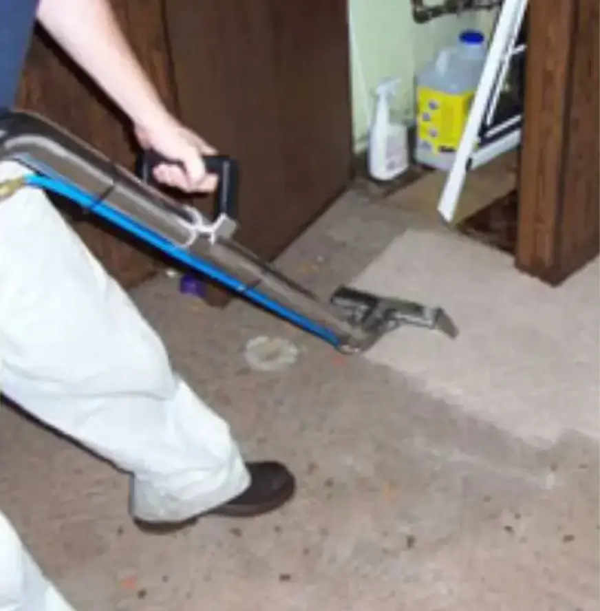Technician pushing an extraction wand across a wet floor to pull out water in a La Habra home