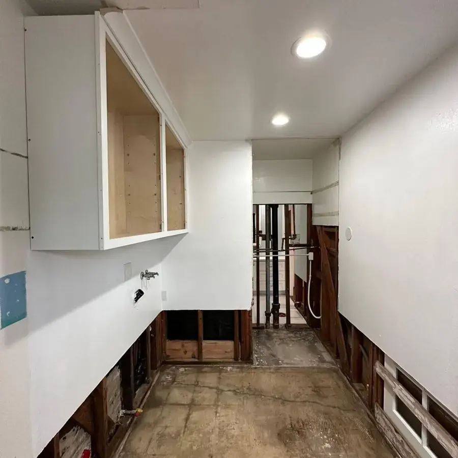 Galley kitchen in La Habra with the lower cabinets and drywall cut out so the walls can dry